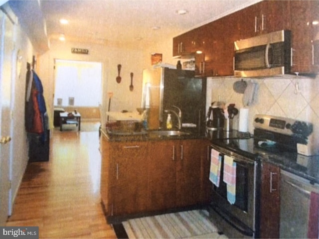 kitchen with sink, stainless steel appliances, and light hardwood / wood-style floors