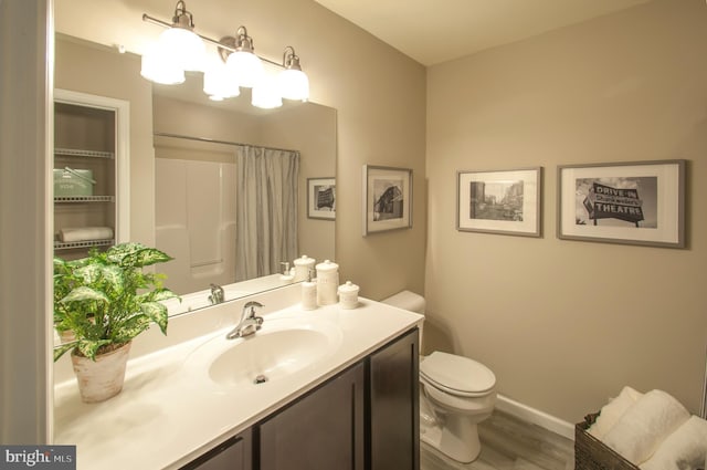 bathroom featuring hardwood / wood-style floors, toilet, and vanity with extensive cabinet space