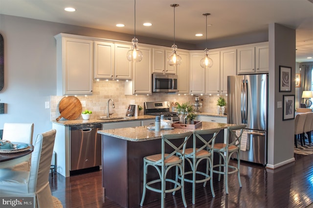 kitchen with hanging light fixtures, white cabinets, appliances with stainless steel finishes, and dark hardwood / wood-style flooring