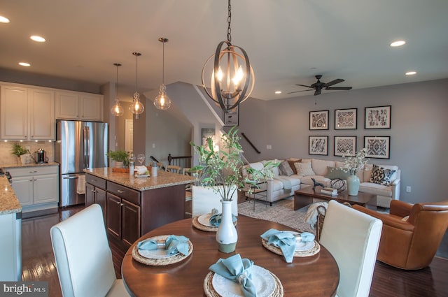 dining room featuring ceiling fan with notable chandelier and dark hardwood / wood-style flooring