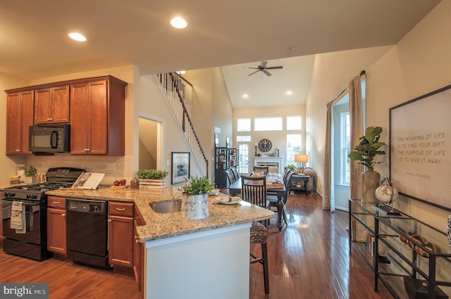 kitchen featuring ceiling fan, light stone countertops, dark hardwood / wood-style floors, and black appliances