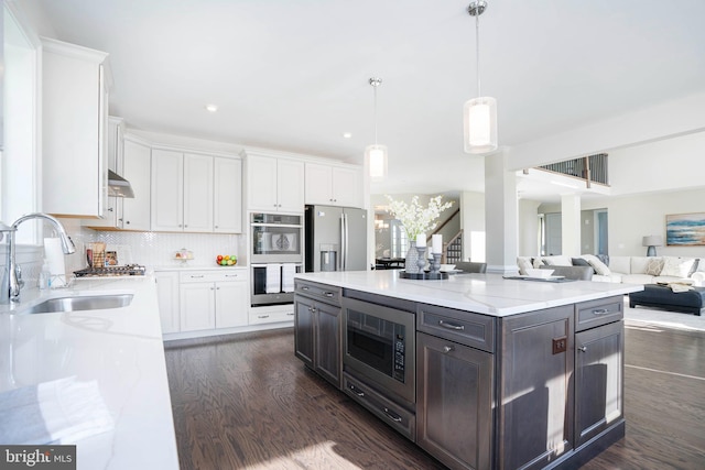 kitchen featuring a center island, white cabinets, hanging light fixtures, sink, and appliances with stainless steel finishes