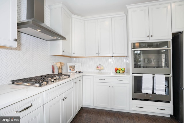 kitchen with appliances with stainless steel finishes, white cabinetry, and wall chimney exhaust hood