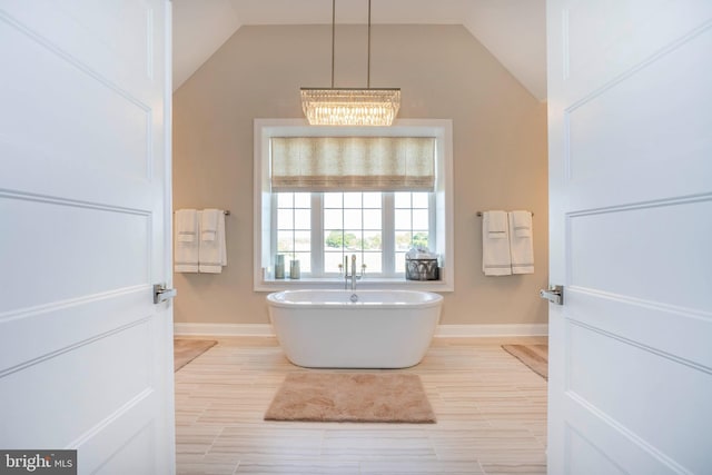 bathroom with a bathtub, vaulted ceiling, and an inviting chandelier