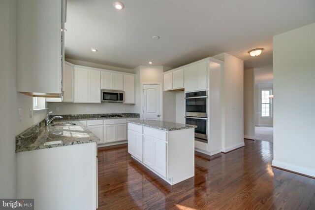 kitchen featuring white cabinetry, dark wood-type flooring, light stone counters, and stainless steel appliances