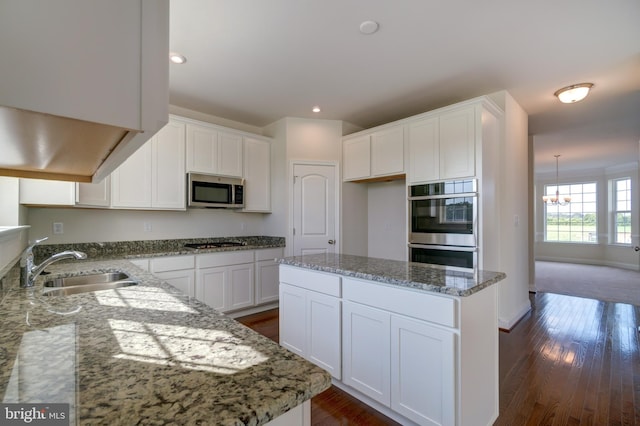 kitchen featuring dark wood-type flooring, a kitchen island, light stone counters, and stainless steel appliances