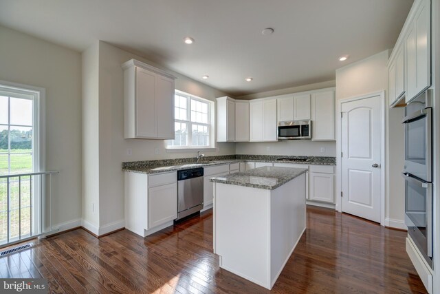 kitchen with dark hardwood / wood-style flooring, white cabinets, a healthy amount of sunlight, and stainless steel appliances