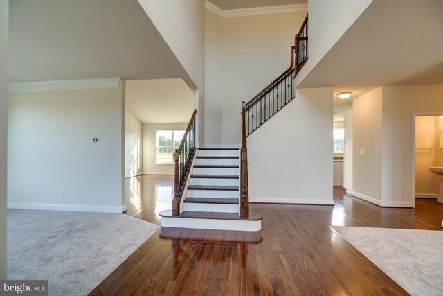 stairway featuring dark carpet and ornamental molding