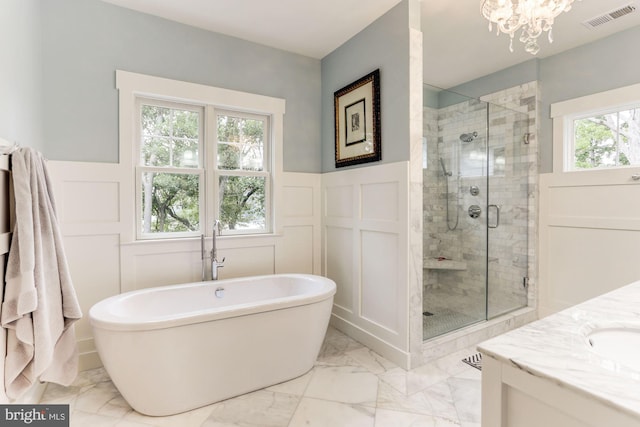 bathroom with a notable chandelier, vanity, and plus walk in shower