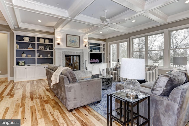 living room with a high end fireplace, coffered ceiling, light hardwood / wood-style flooring, ceiling fan, and beamed ceiling