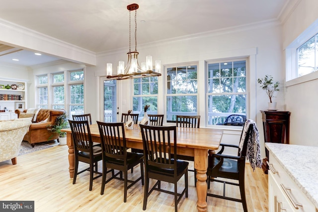 dining space with crown molding, light hardwood / wood-style flooring, and a chandelier