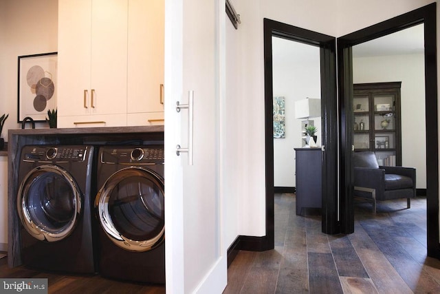 laundry area with dark hardwood / wood-style flooring, washing machine and clothes dryer, and cabinets