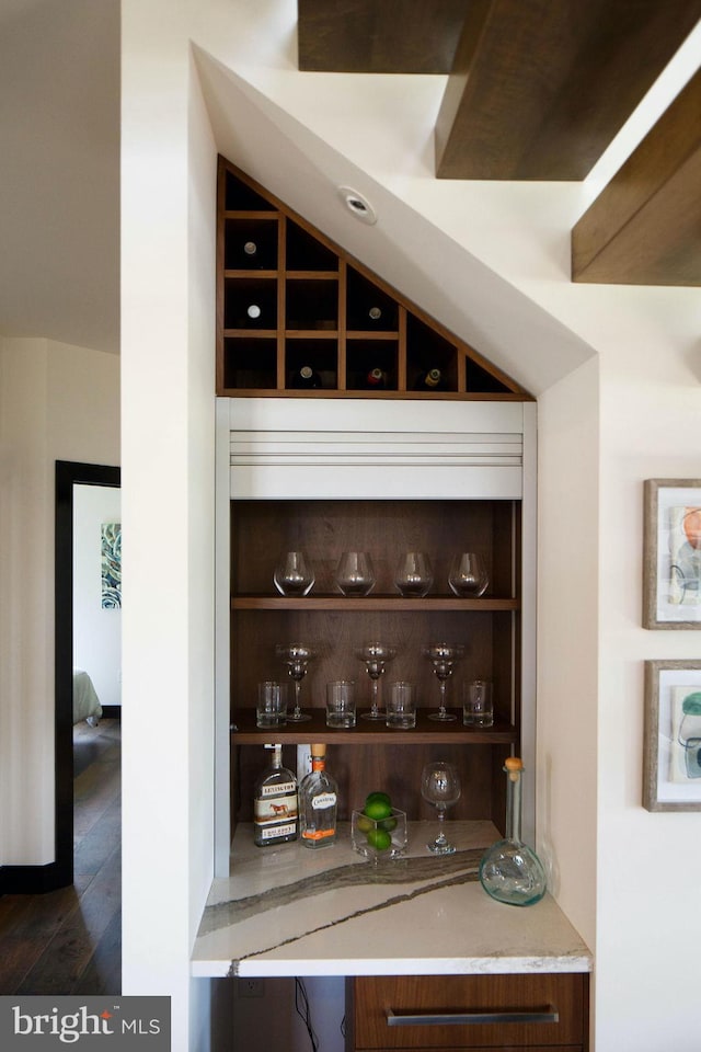 bar featuring dark wood-type flooring and light stone counters