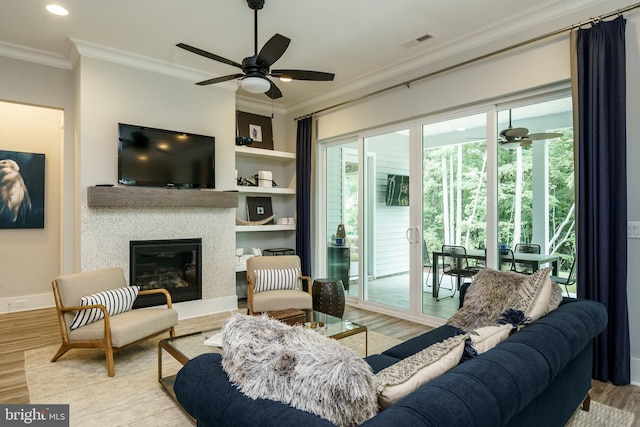 living room with built in shelves, ornamental molding, light hardwood / wood-style floors, and ceiling fan