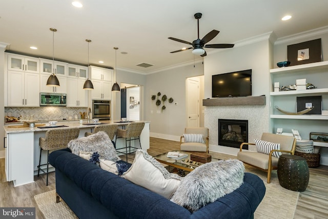 living room with light hardwood / wood-style flooring, ceiling fan, sink, and ornamental molding