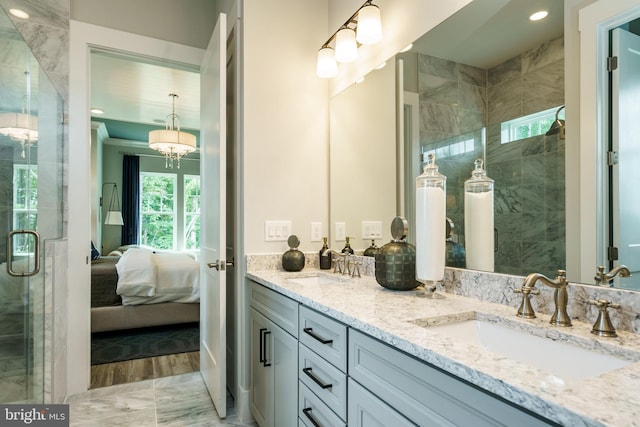 bathroom with an inviting chandelier, double sink vanity, a shower with shower door, and hardwood / wood-style floors