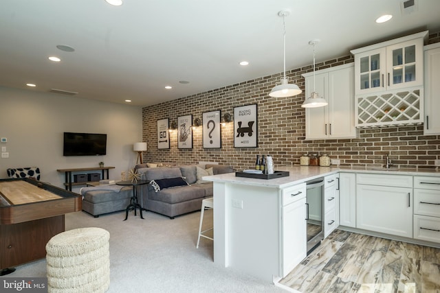 kitchen with light carpet, white cabinets, a kitchen bar, beverage cooler, and pendant lighting