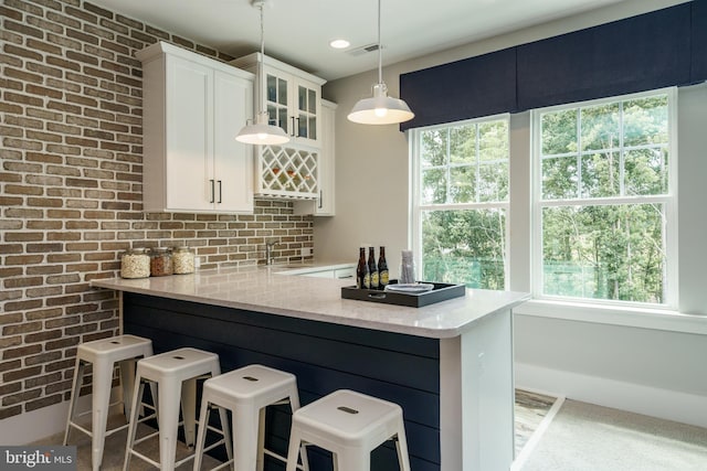 bar featuring decorative light fixtures, a healthy amount of sunlight, and white cabinetry