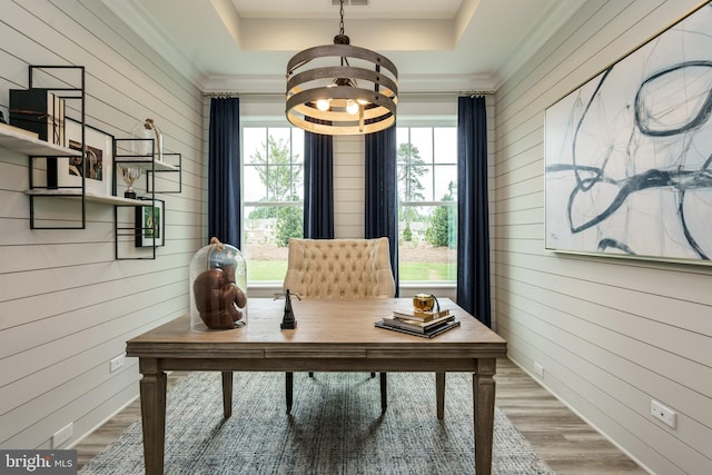 office area featuring crown molding, light wood-type flooring, and a raised ceiling