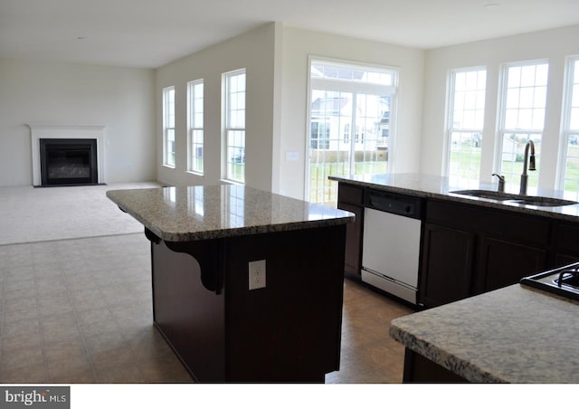 kitchen featuring sink, a kitchen island, white dishwasher, and a healthy amount of sunlight