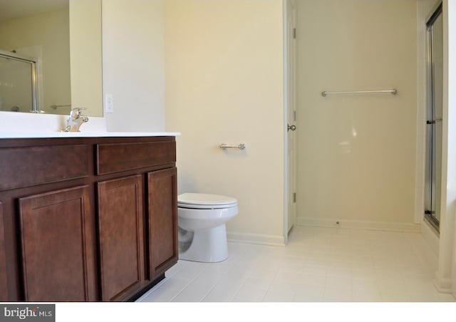 bathroom with toilet, tile flooring, a shower with shower door, and vanity