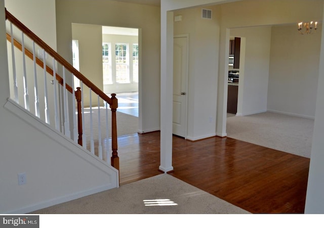 entrance foyer featuring an inviting chandelier and dark colored carpet