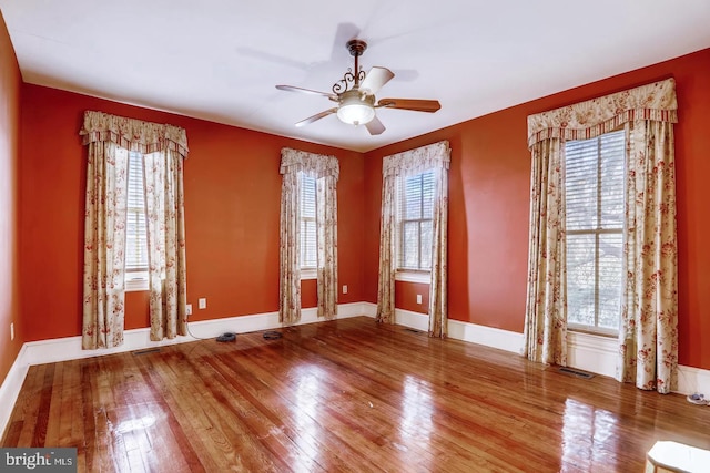 spare room featuring dark hardwood / wood-style floors, ceiling fan, and a wealth of natural light