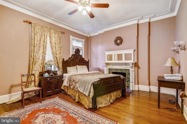 bedroom with crown molding, hardwood / wood-style floors, and a fireplace