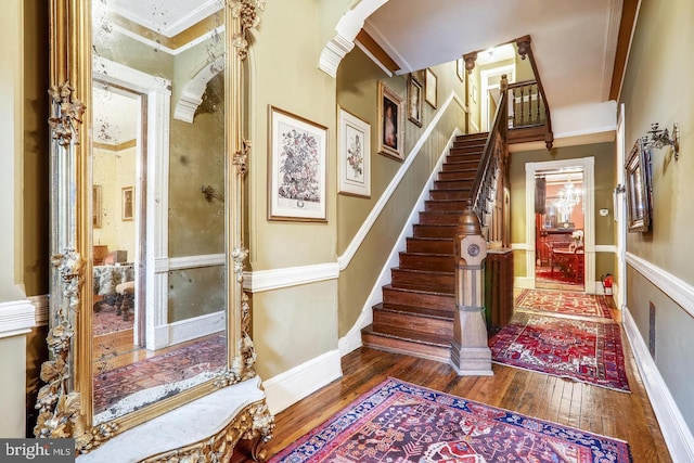 entryway featuring dark hardwood / wood-style flooring, crown molding, and decorative columns