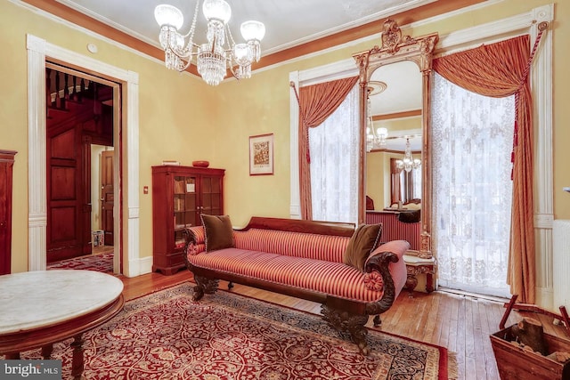 living area with a chandelier, crown molding, and light wood-type flooring