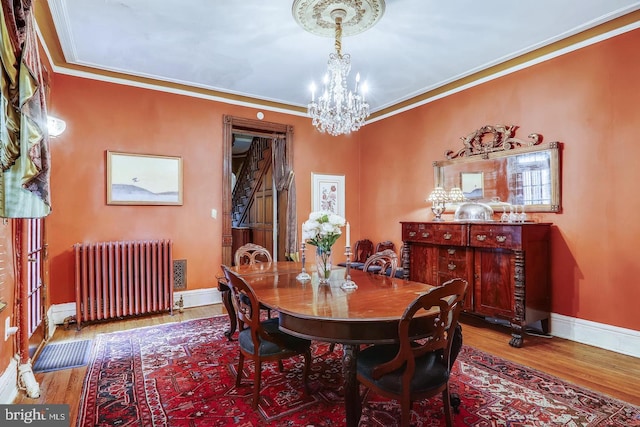 dining area featuring radiator, a chandelier, hardwood / wood-style floors, and crown molding