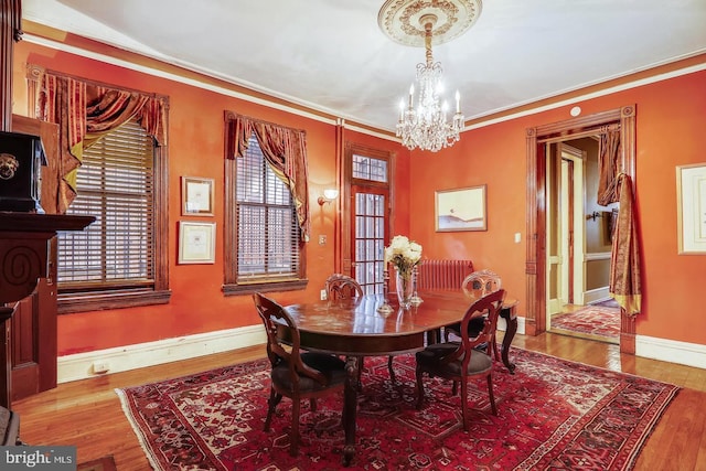 dining area featuring dark hardwood / wood-style flooring, a notable chandelier, and crown molding