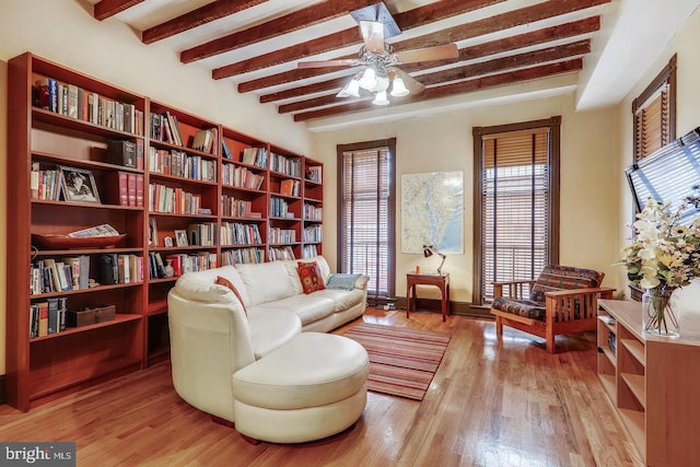 living area featuring light hardwood / wood-style floors, ceiling fan, and beamed ceiling