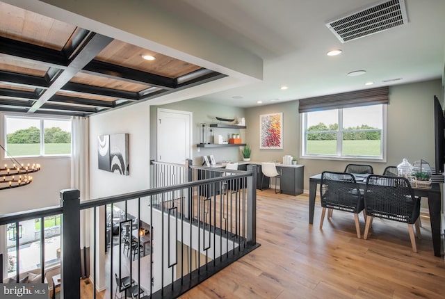 corridor with an inviting chandelier, coffered ceiling, beamed ceiling, and a wealth of natural light