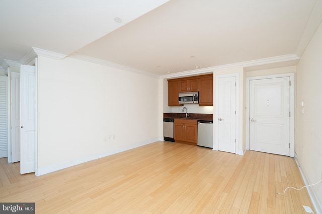 unfurnished living room featuring light hardwood / wood-style flooring, ornamental molding, and sink