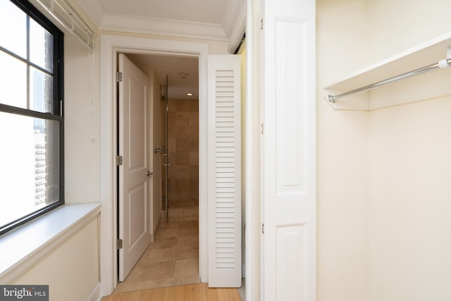 hall featuring crown molding, light tile flooring, and a wealth of natural light