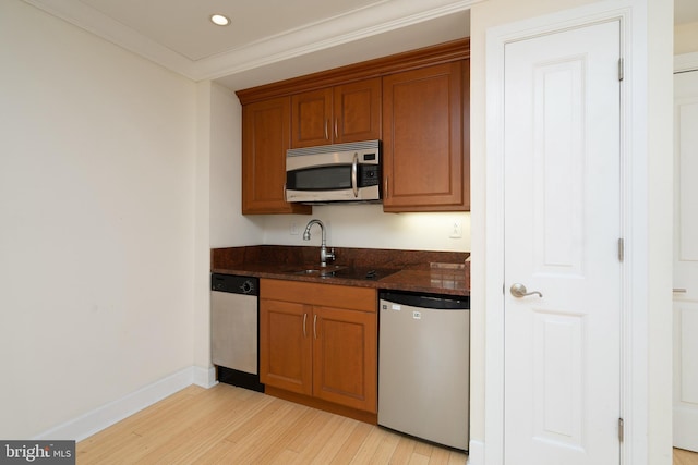 kitchen featuring dark stone countertops, appliances with stainless steel finishes, crown molding, and light hardwood / wood-style floors