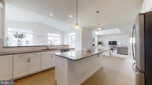 kitchen featuring pendant lighting, dark stone counters, stainless steel refrigerator, lofted ceiling, and white cabinets