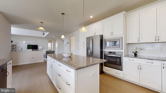 kitchen with light hardwood / wood-style floors, stainless steel appliances, white cabinets, a kitchen island, and tasteful backsplash