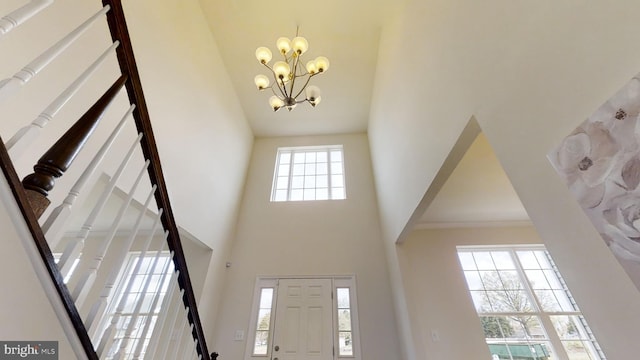 foyer featuring a towering ceiling, crown molding, and a chandelier