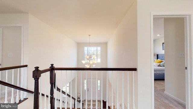 corridor featuring light colored carpet and a notable chandelier