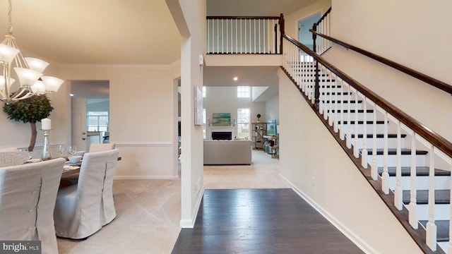 foyer featuring a high ceiling, a chandelier, a healthy amount of sunlight, and light hardwood / wood-style flooring