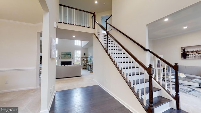 stairway featuring light hardwood / wood-style flooring, a towering ceiling, and crown molding