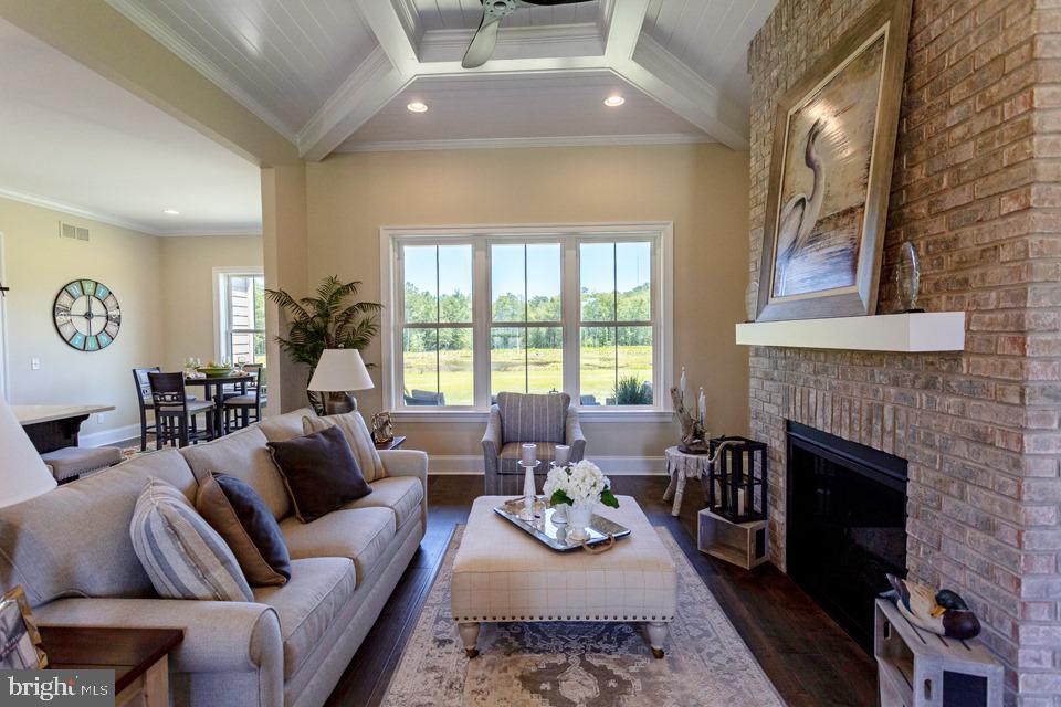 living room with beam ceiling, crown molding, dark hardwood / wood-style floors, and a fireplace