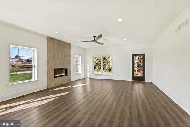 unfurnished living room with ceiling fan, dark wood-type flooring, a large fireplace, and plenty of natural light