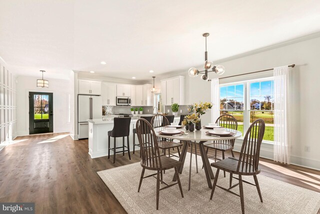 dining area with crown molding, dark hardwood / wood-style floors, an inviting chandelier, and sink