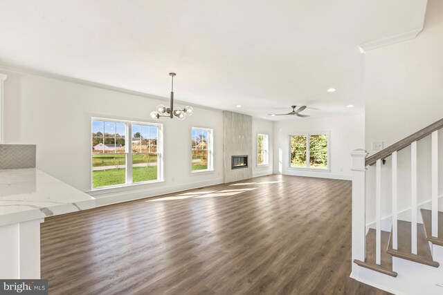 unfurnished living room featuring dark hardwood / wood-style flooring, a large fireplace, and ceiling fan with notable chandelier