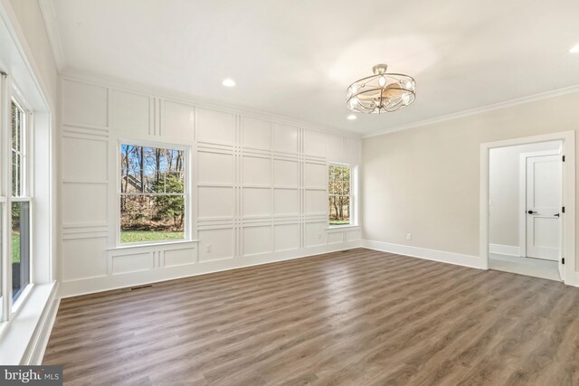 unfurnished room featuring dark hardwood / wood-style floors, ornamental molding, and a chandelier