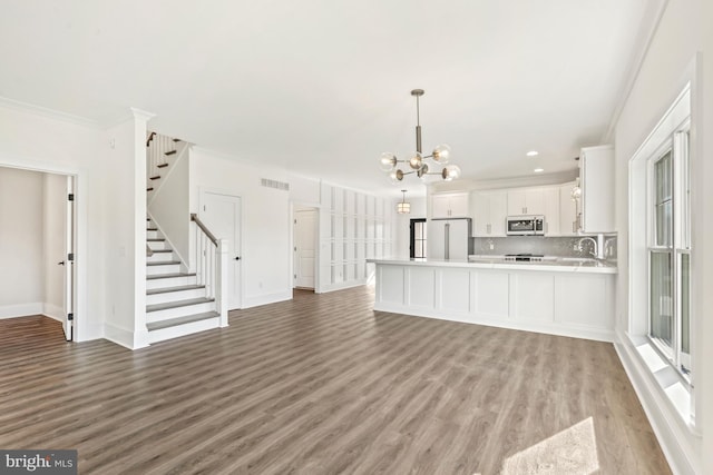 unfurnished living room featuring crown molding, light hardwood / wood-style floors, and a notable chandelier