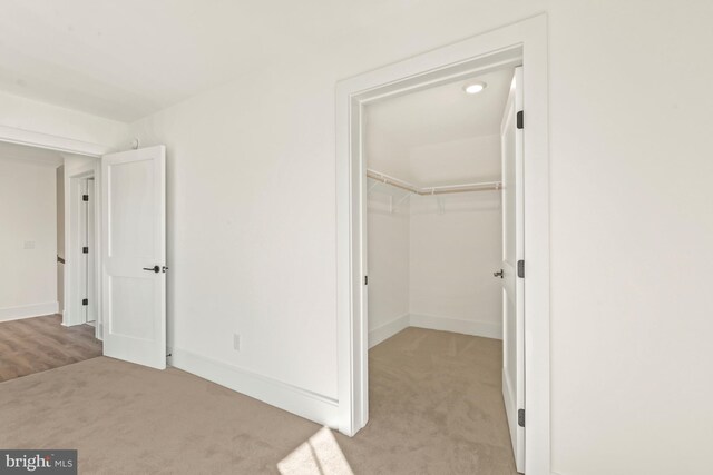 unfurnished bedroom featuring light carpet, a closet, and a walk in closet